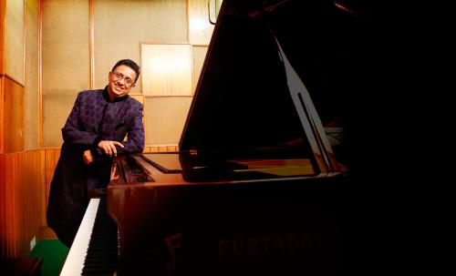 Deepak Shah, standing beside Piano